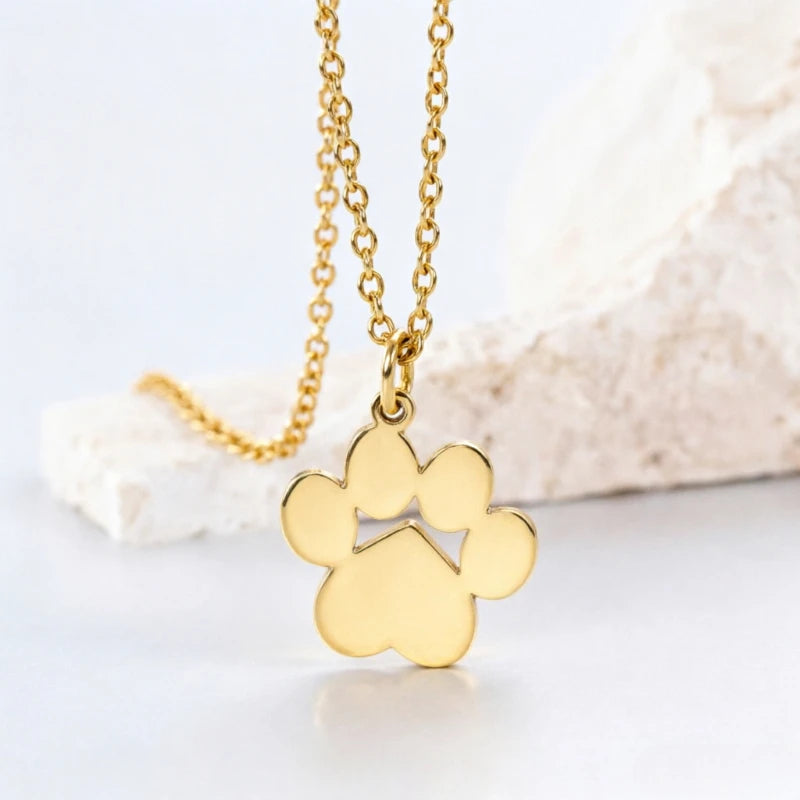A gold-colored stainless steel cat paw pendant necklace displayed on a white surface.