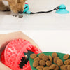 A hand holds a red and blue interactive suction cup tug dog ball with food dispensing function.