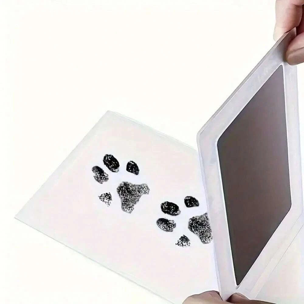 A clear plastic kit containing pet paw prints is being held by a hand.