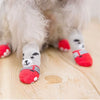 A close-up of a fluffy pet's paws wearing anti-slip socks with paw prints and red accents.