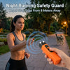 A woman uses a portable orange ultrasonic device to repel stray dogs from eight meters away in a park setting.