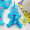 A bright blue dinosaur fleece pet hoodie with purple polka dots and a yellow fan in the background.