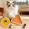 A fluffy white cat is sitting next to an orange loofah chewing toy with catnip.