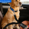 A golden retriever wearing a blue dog car safety belt with a black harness and reflective strip sitting in a car seat.