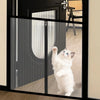 A white kitten is visible through a black metal mesh pet gate and barrier.