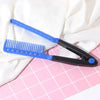 Peigne de cheveux en forme de V bleu et noir posé sur une surface à grille rose avec du tissu blanc.