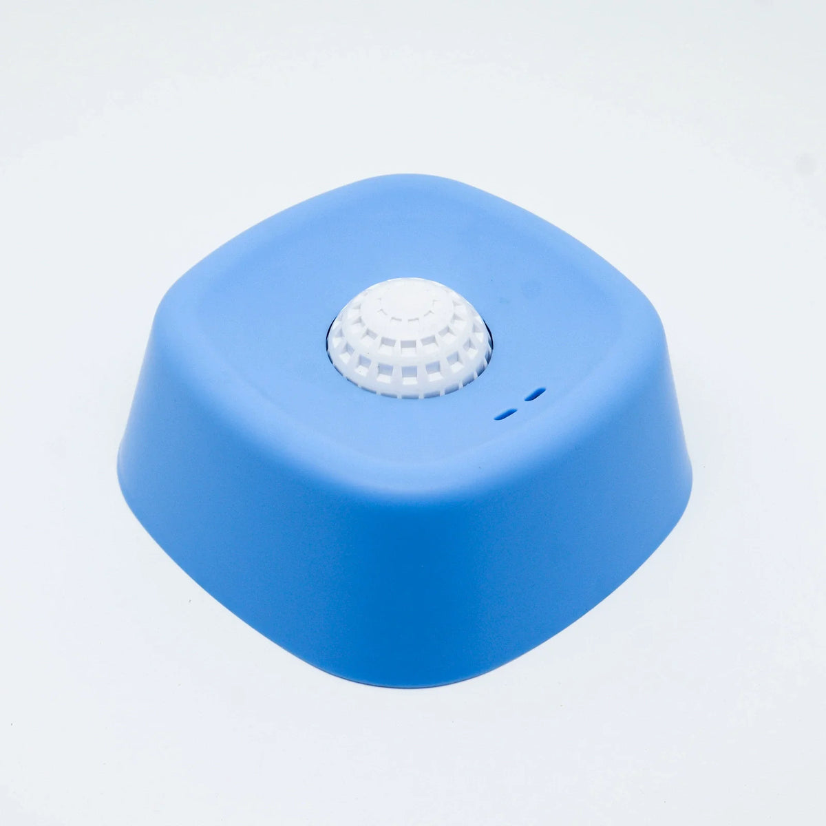 A bright blue silicone lick bowl with a white textured disc on top.