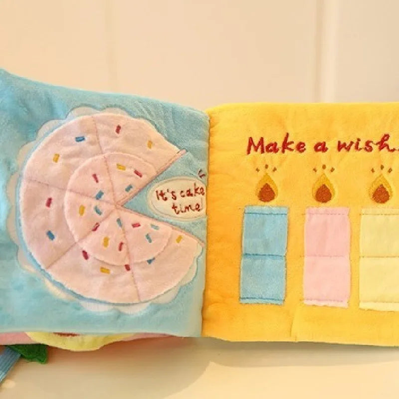 A pair of soft fabric toys, one blue with a cake shape and another yellow with the text Make a wish.