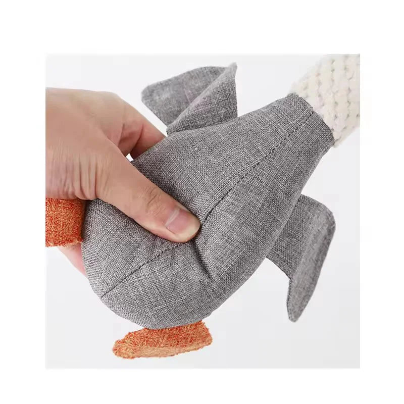 A hand is holding a gray plush dog toy with white and orange accents.