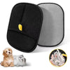 A pair of black and gray double-sided pet grooming gloves for hair removal and cleaning shown next to a dog's fur.