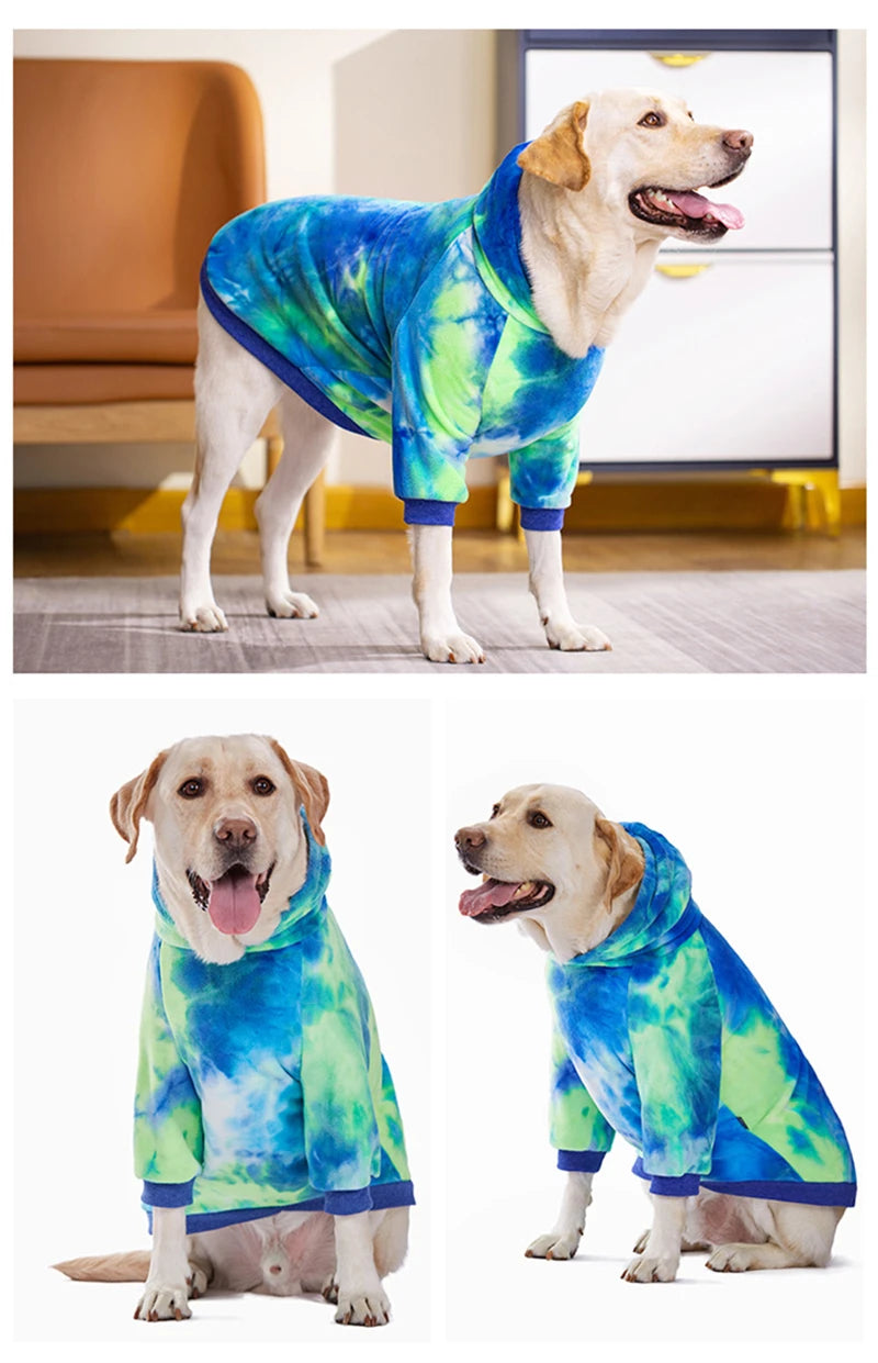 A golden retriever wearing a blue and green tie-dye fleece dog hoodie standing on a floor.