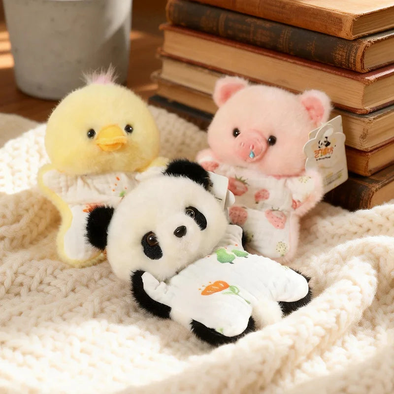 Three soft plush toys of a yellow chick, pink pig, and white panda resting on a cream knitted fabric.