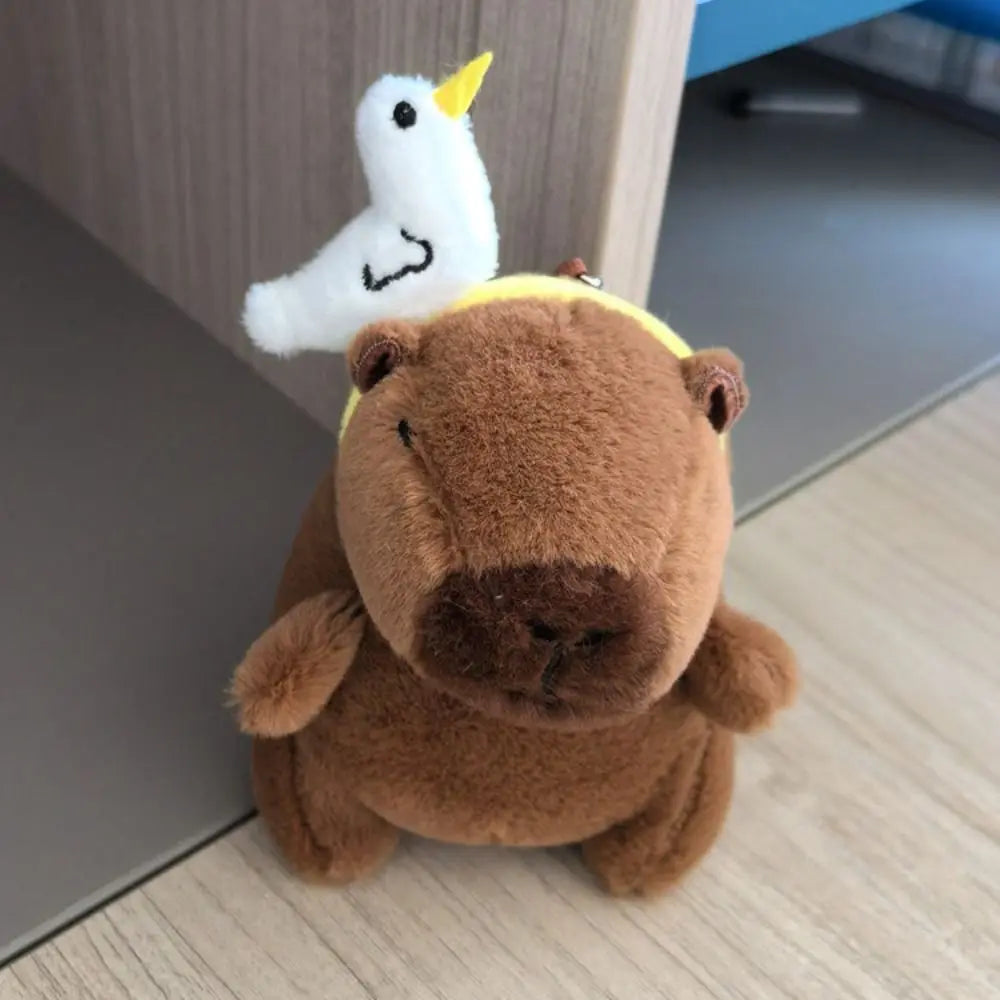 A brown capybara plush toy with a white, yellow-tipped wing attached.