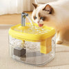 A clear cat drinking fountain with a yellow base is being used by a white and brown cat.