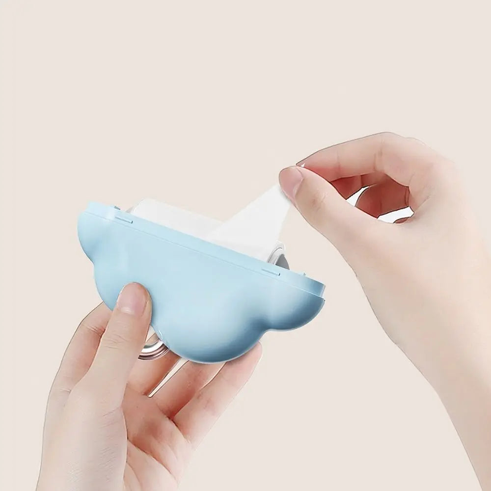 A hand holds a light blue cloud-shaped lint roller refill with white sheets against a plain background.