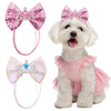 Ein flauschiger weißer Hund trägt ein rosa gerafftes Kleid und eine passende rosa Haartülle.