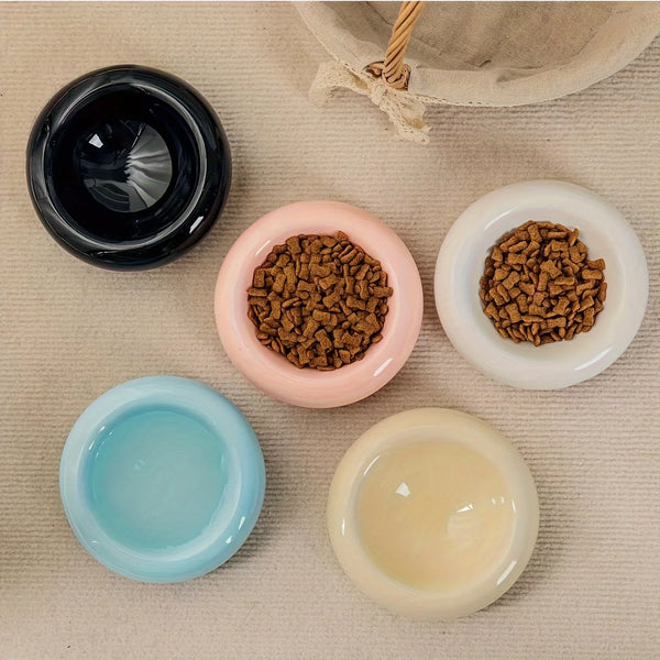A collection of ceramic pet bowls in various colors and textures, including black, pink, white, and light yellow.