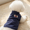 A navy blue summer pet sleeveless vest with a white fluffy dog and red embroidery lying on a cream rug.