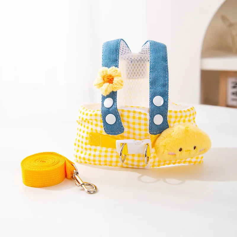 Harnais à carreaux jaunes avec accents bleus et un charm de ours jaune, accompagné d'une laisse orange.