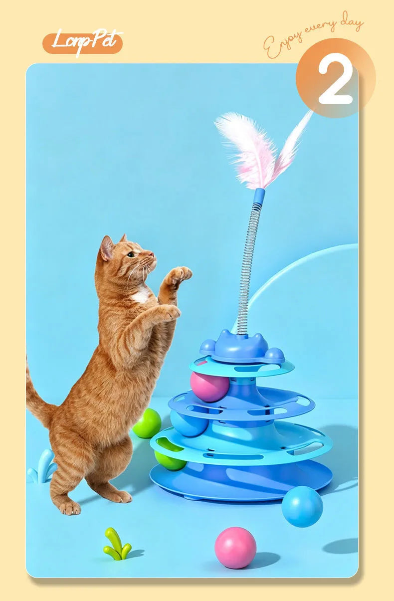 A fluffy orange cat interacts with a blue interactive toy featuring a feather wand and rolling balls.