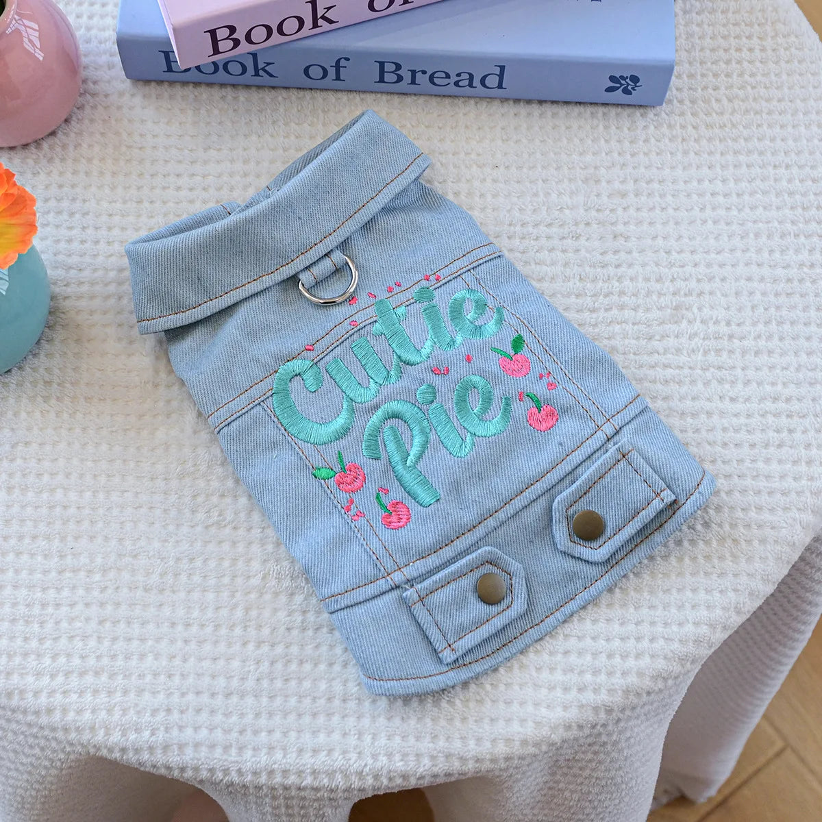 A light blue denim jacket for dogs embroidered with the text Cutie Pie