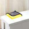 Une pile de serviettes de bain ultra-absorbantes pour animaux jaunes et grises posées sur une table blanche.