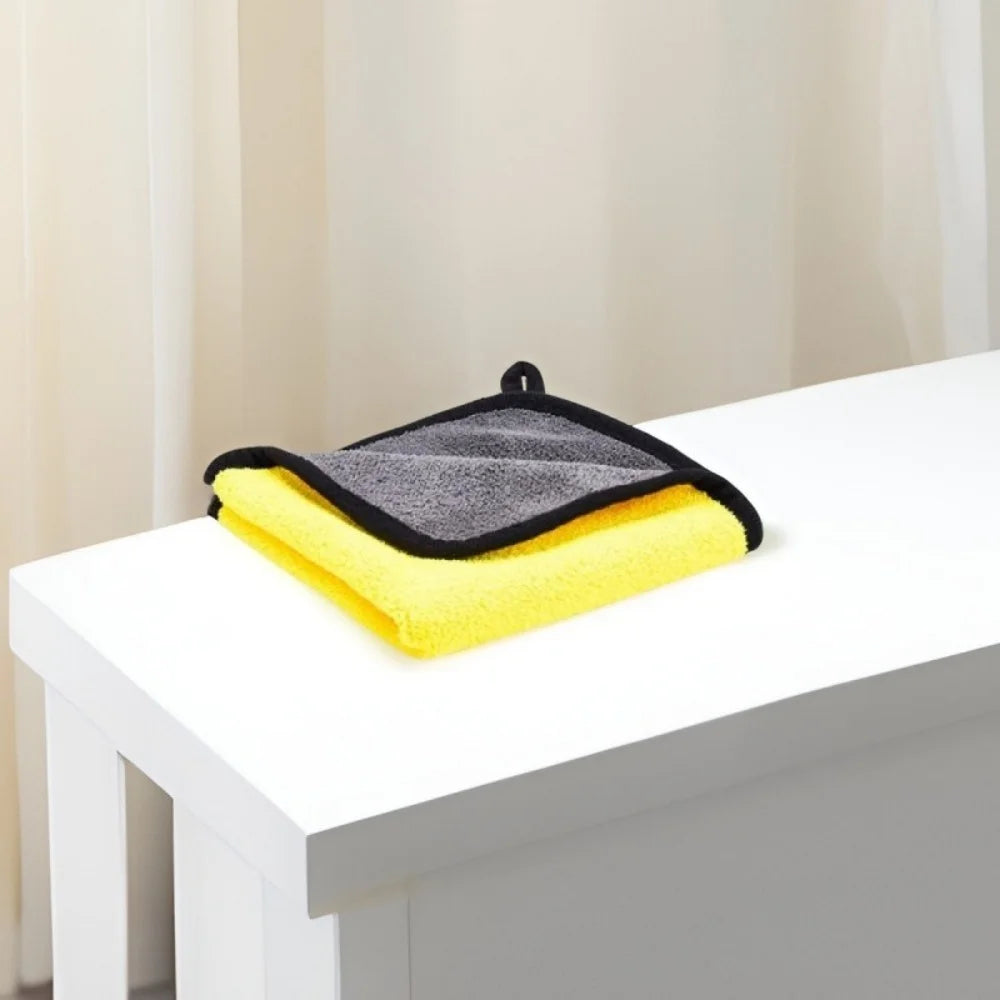 Une pile de serviettes de bain ultra-absorbantes pour animaux jaunes et grises posées sur une table blanche.