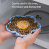 A hand holds a silicone lick mat filled with dog food, demonstrating its use in an oven, microwave, and dishwasher.
