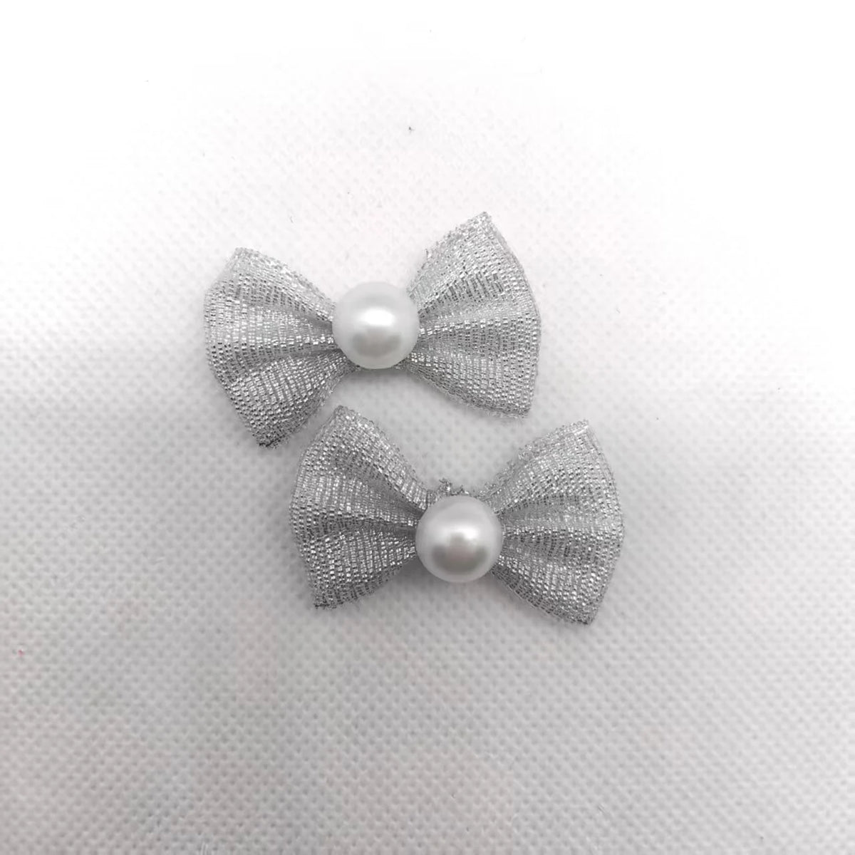 Ein Set aus drei silbernen Glitzer-Bowknoten mit Perlmitten für das Pflegen von Haustieren.