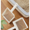 A white extra-large cat litter scoop with a hanging hook resting on a wooden surface.