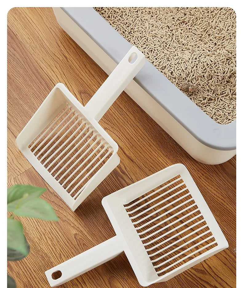 A white extra-large cat litter scoop with a hanging hook resting on a wooden surface.
