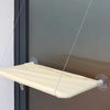 A beige hammock bed suspended by thin cords and suction cups, designed for a cat window.