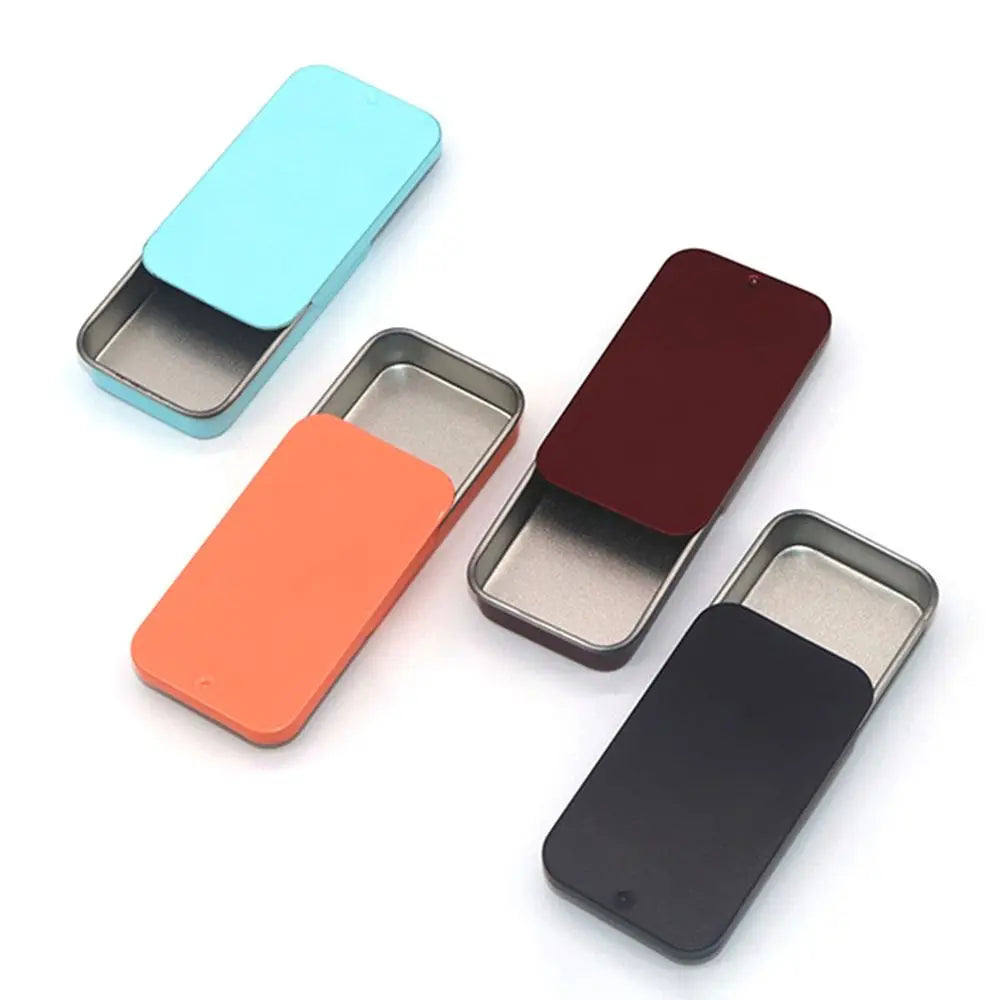 A collection of four compact sliding lid tin boxes in various colors including light blue, orange, maroon, and black.