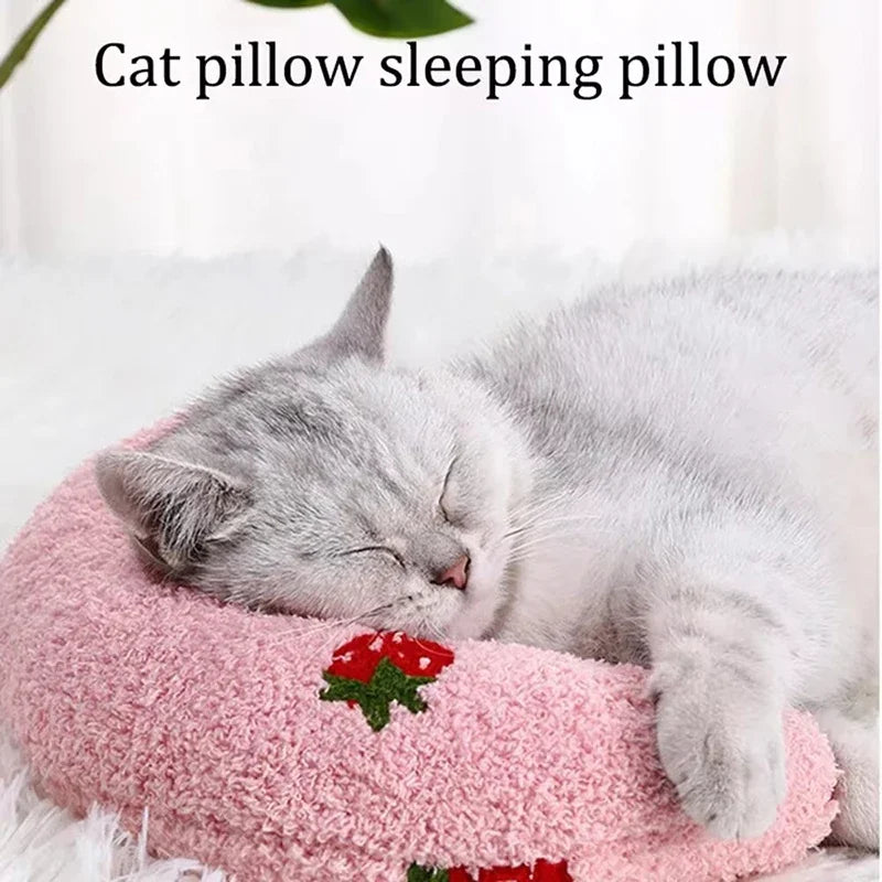 Un chaton gris et duveteux dort paisiblement sur un coussin d'animal rose.