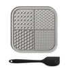 A gray silicone lick mat for pets is shown next to a black silicone spoon.