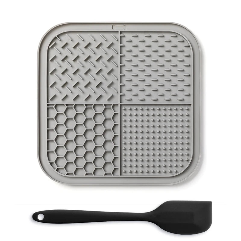 A gray silicone lick mat for pets is shown next to a black silicone spoon.