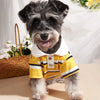 A small dog wearing a yellow and black striped polo shirt against a white background.