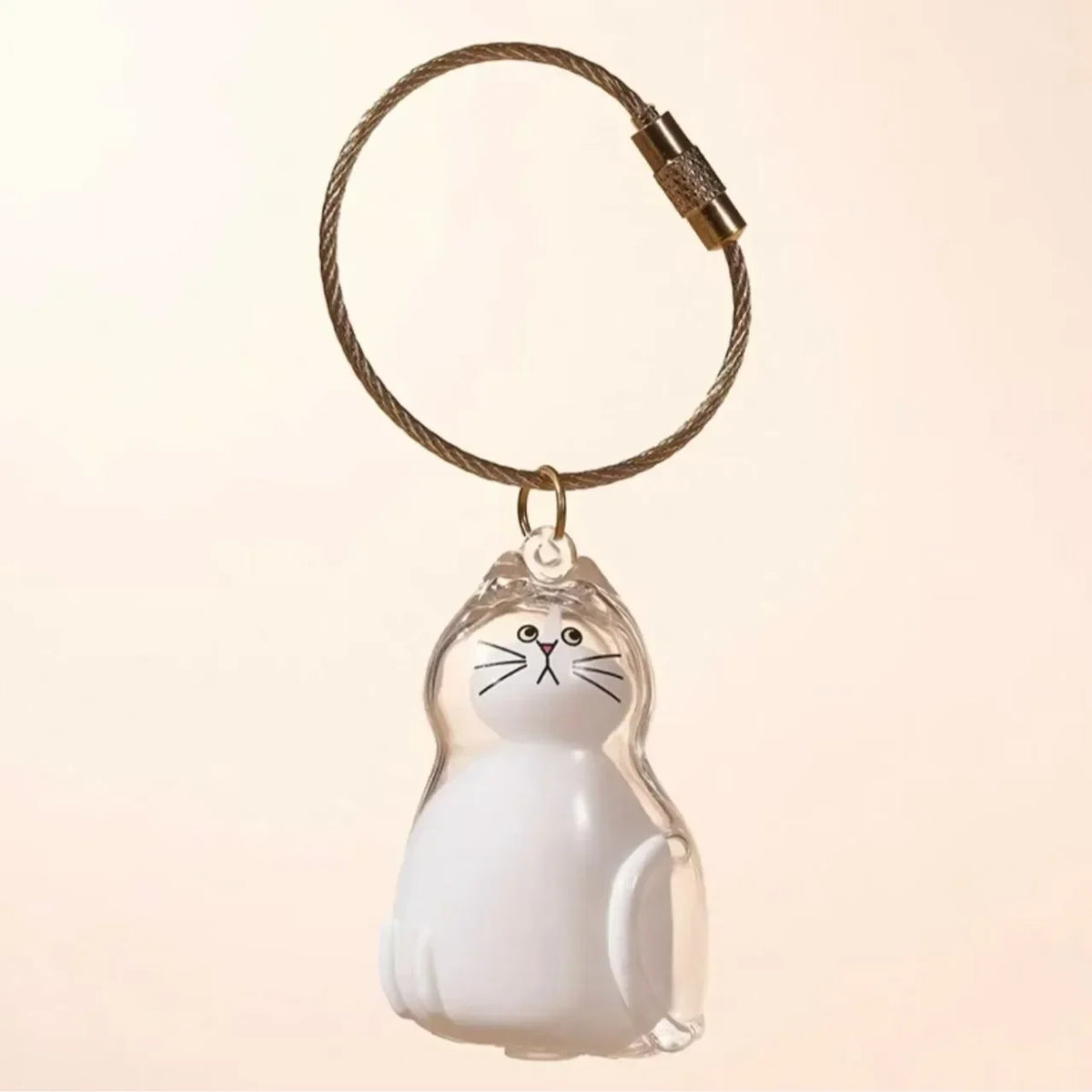 Un charm de chat sculpté et clair attaché à une clé USB en cuir tressé.