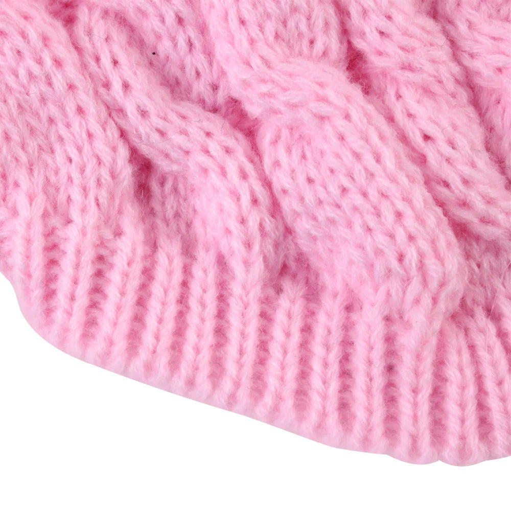 Gros plan d'un pull tricoté rose avec un motif torsades.