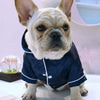 A fawn-colored French Bulldog wearing a dark blue silk pet pajama top.