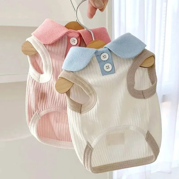 A white and pink breathable cotton dog shirt for a small breed hanging on a wooden hanger.