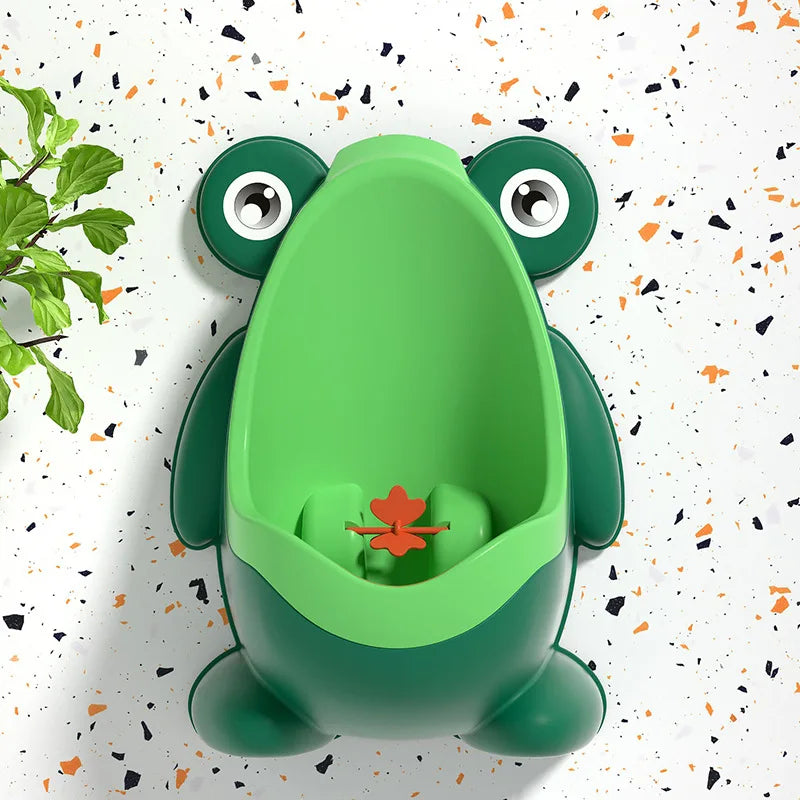 Un entrenador para el entrenamiento de ir al baño en forma de rana verde brillante con un pequeño detalle de hoja naranja.