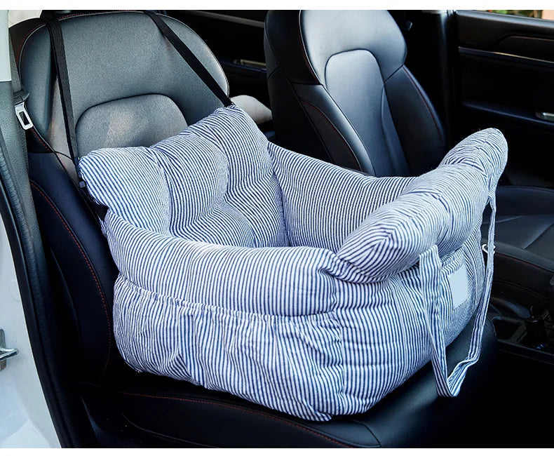 A striped blue and white pet car seat with safety straps is shown inside a dark car interior.