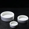 A set of three white ceramic reptile feeding and watering bowls placed on a dark surface.