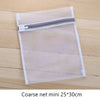 Una bolsa de ropa de malla transparente con cremallera gris sobre una superficie de madera.