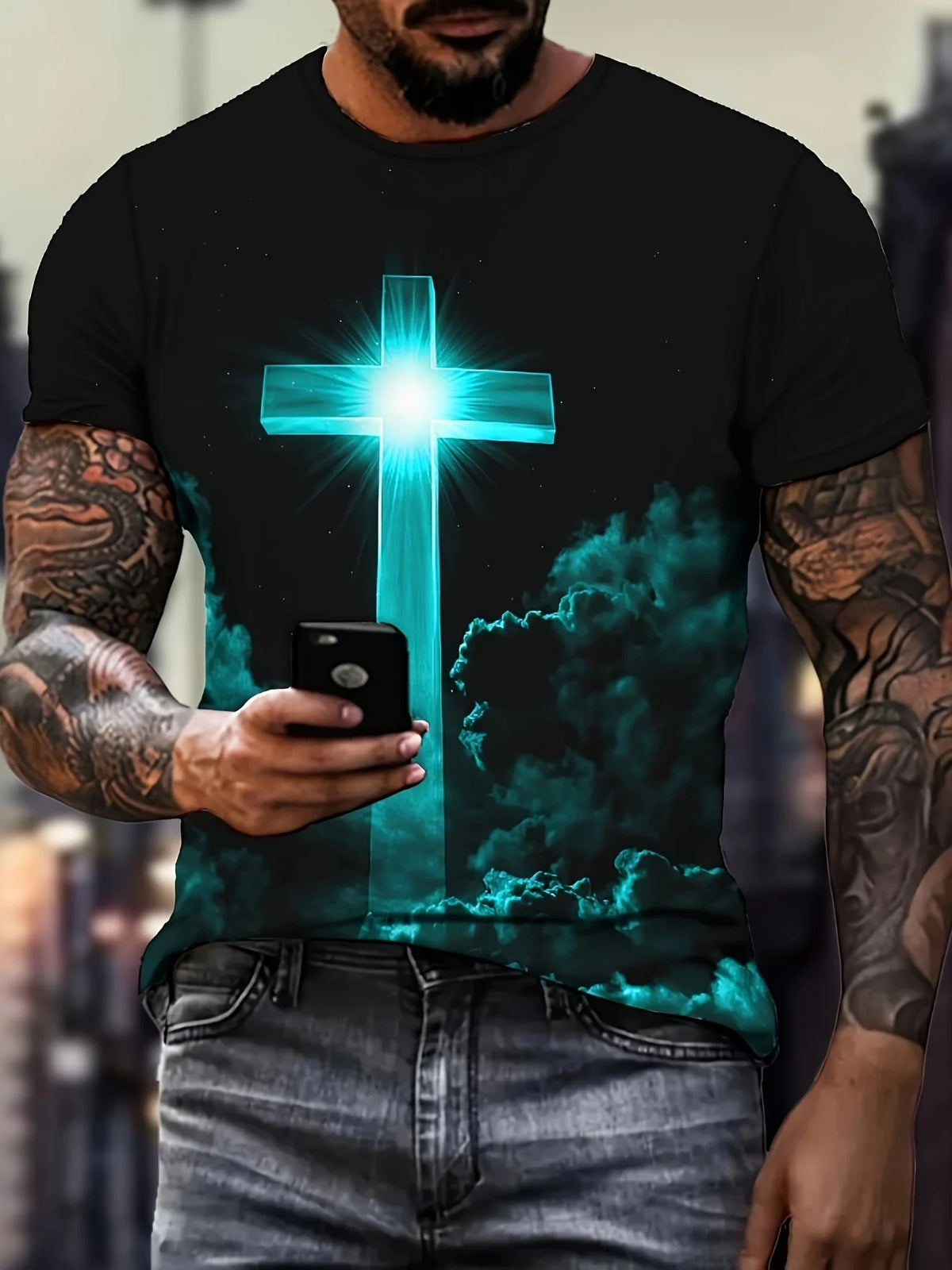 A man wearing a dark t-shirt with a glowing blue cross design and jeans.