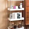 A white mobile storage rack with three tiers holding various small items and jars.