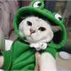 A white cat wearing a green frog-themed hoodie with large eyes.