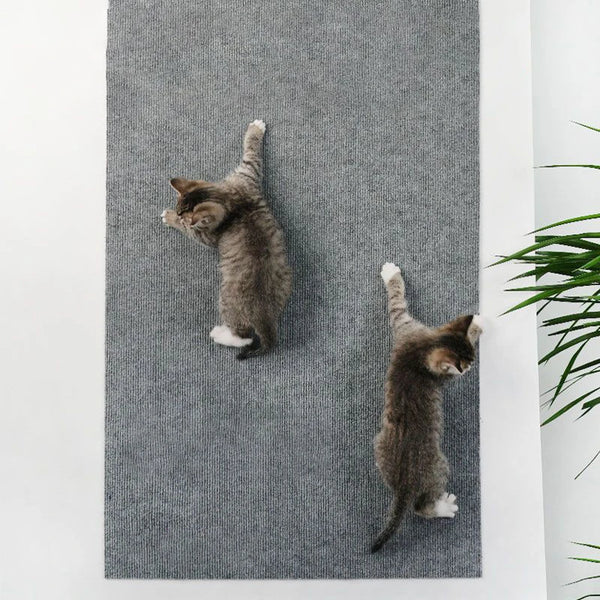 A gray knitted cat scratching mat with two small tabby kittens playing on it.