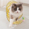 A fluffy gray and white cat is playing inside a yellow, colorful foldable hunting tunnel for indoor play.